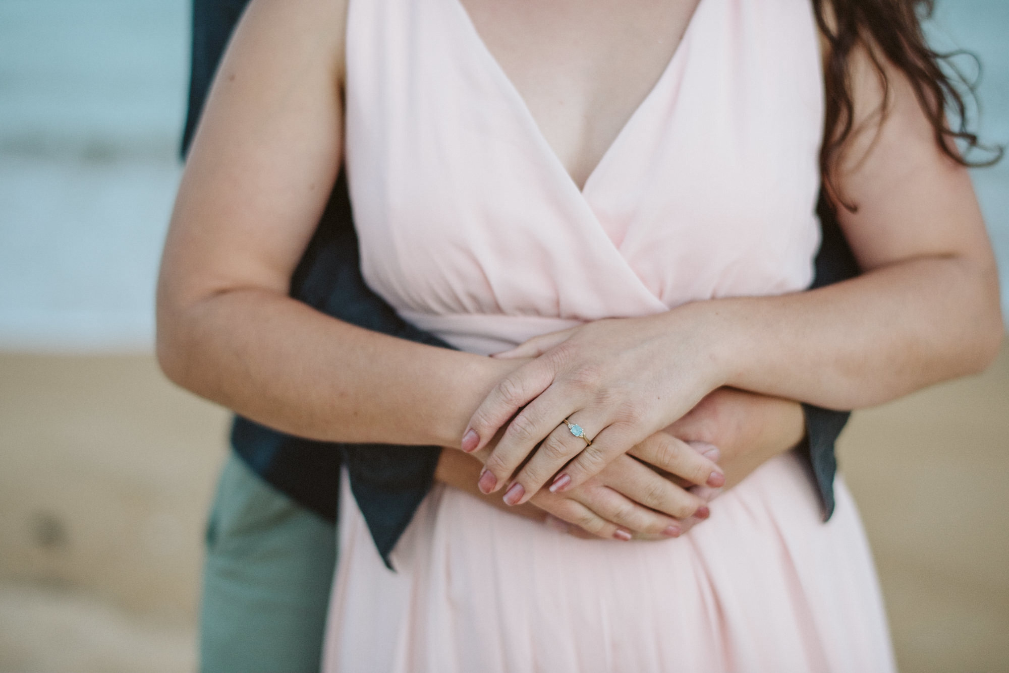 A close up image of hands showing a blue engagement ring