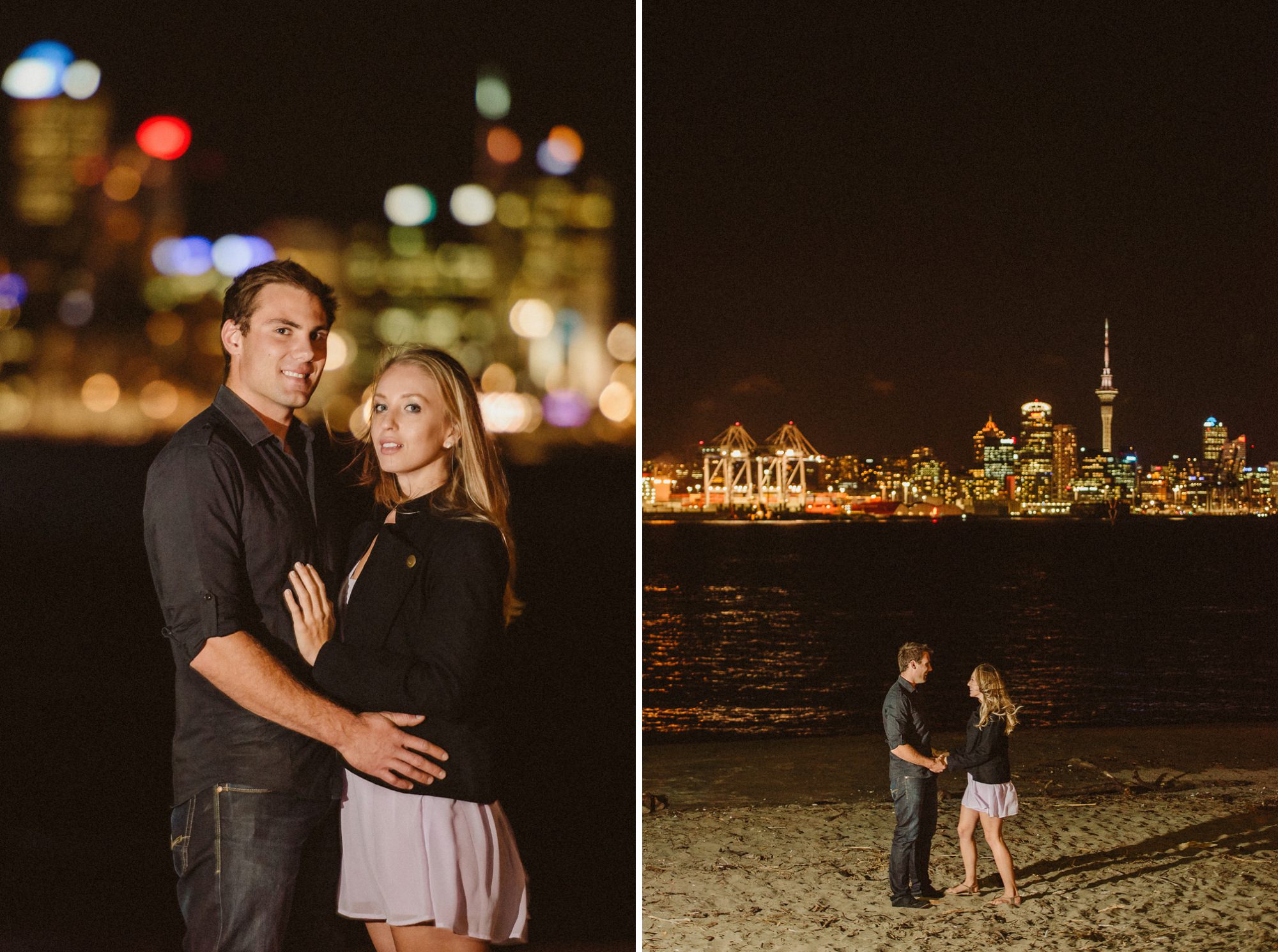 A couple stand on a beach in Devonport with the Auckland skyline in the background at night